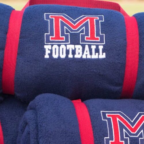 Collection of custom school and team fleece blankets featuring embroidered team logos and school colors.