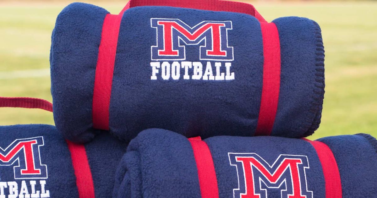 Collection of custom school and team fleece blankets featuring embroidered team logos and school colors.